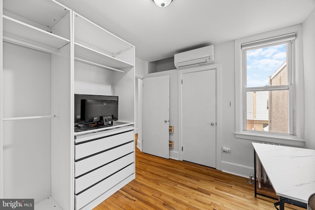 walk in closet with light hardwood / wood-style floors and an AC wall unit