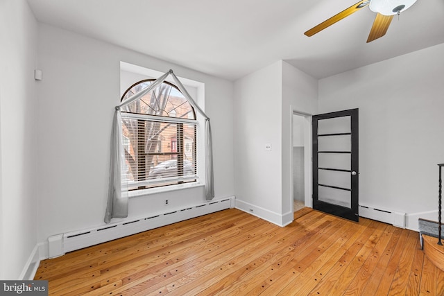 empty room featuring ceiling fan, a baseboard heating unit, and light hardwood / wood-style floors