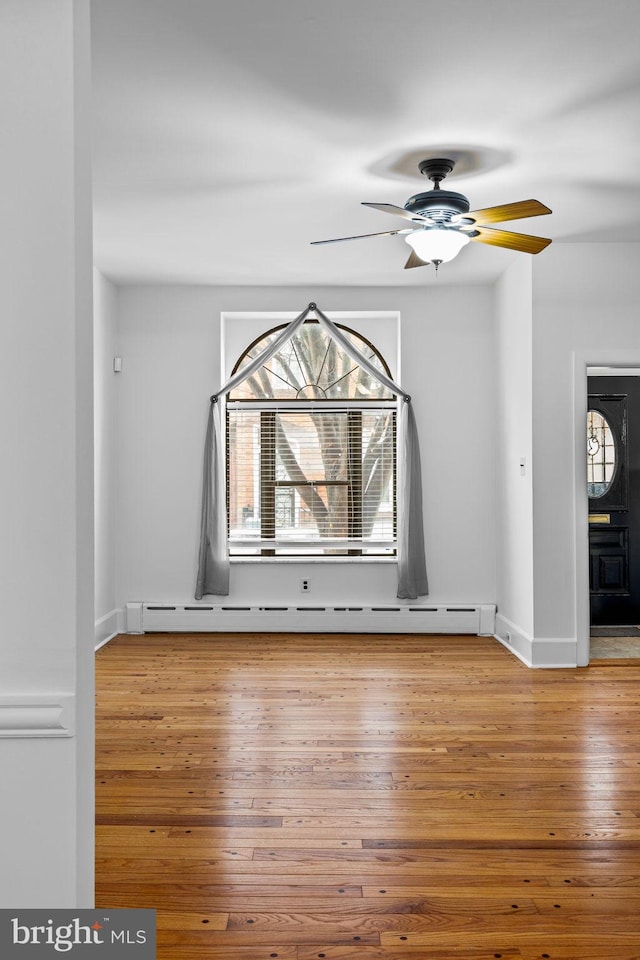 spare room featuring a baseboard radiator, hardwood / wood-style floors, and ceiling fan