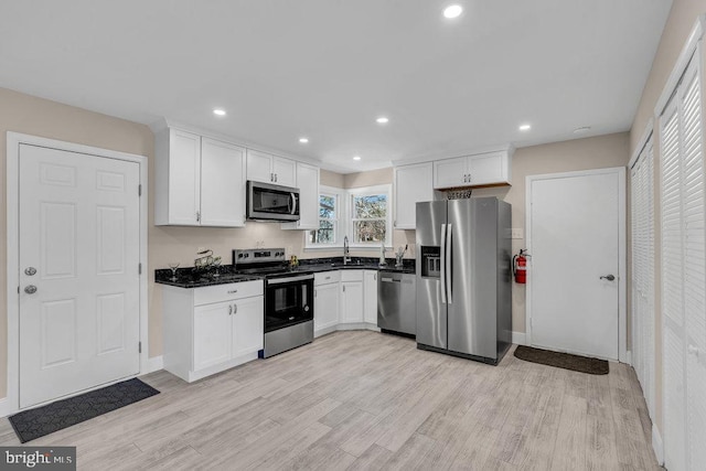 kitchen with appliances with stainless steel finishes, white cabinets, and light wood finished floors