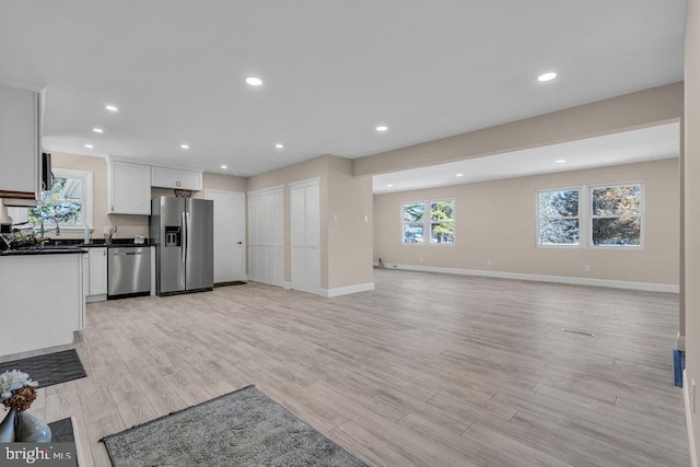 kitchen featuring stainless steel appliances, recessed lighting, baseboards, and light wood finished floors