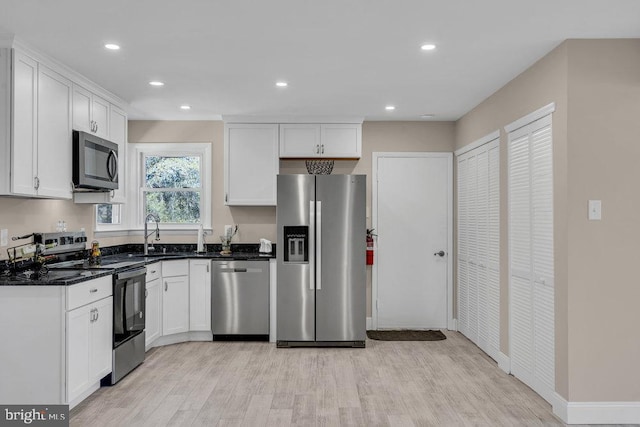 kitchen featuring recessed lighting, a sink, white cabinetry, appliances with stainless steel finishes, and light wood finished floors