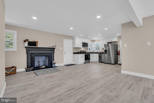 unfurnished living room featuring light wood-type flooring, a fireplace, and baseboards