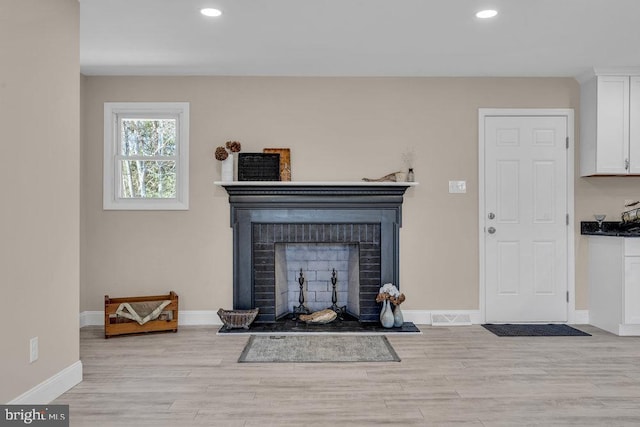 living room featuring recessed lighting, a brick fireplace, light wood-style flooring, and baseboards