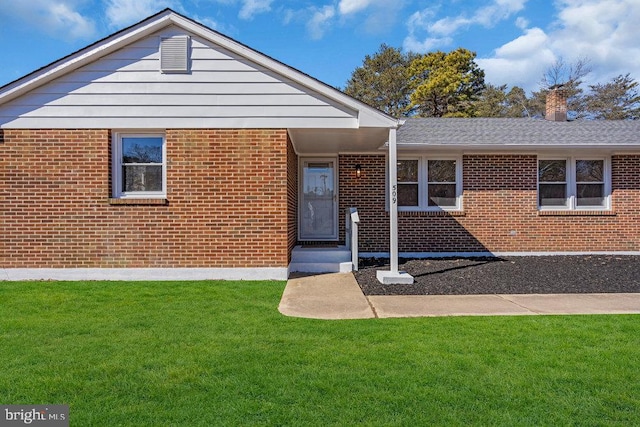 ranch-style house with brick siding, a front lawn, and roof with shingles