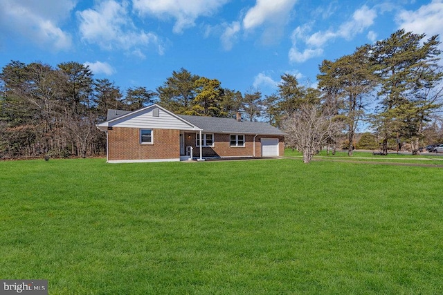 back of property featuring a garage, a yard, and brick siding