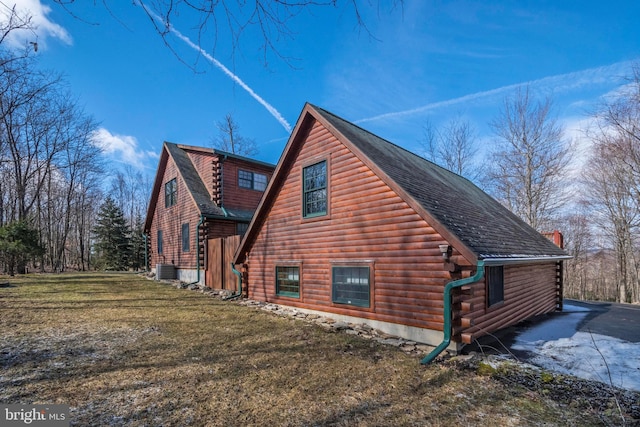 view of side of home with log exterior, a lawn, central AC, and a shingled roof