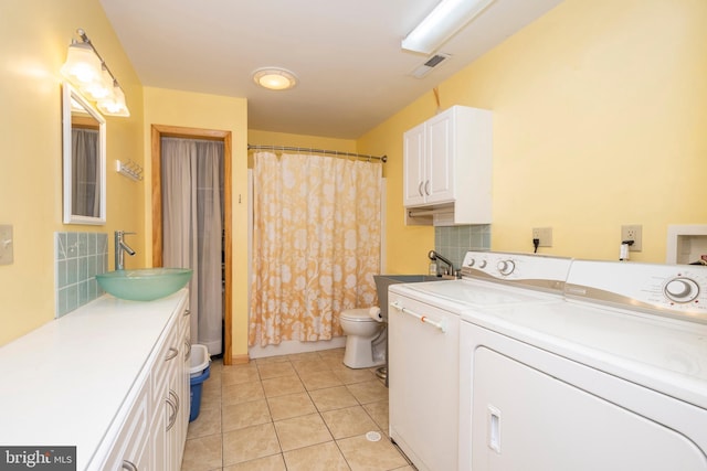 laundry room featuring visible vents, washer and clothes dryer, a sink, light tile patterned floors, and laundry area