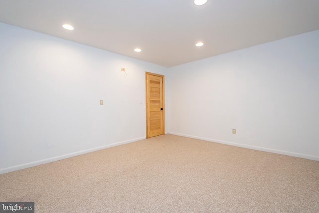 spare room with light carpet, recessed lighting, and baseboards