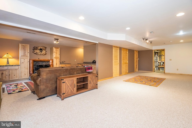 living room with a fireplace, recessed lighting, light colored carpet, and baseboards