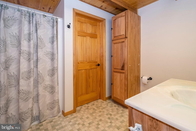 bathroom featuring baseboards, beamed ceiling, wood ceiling, a shower with shower curtain, and tile patterned floors