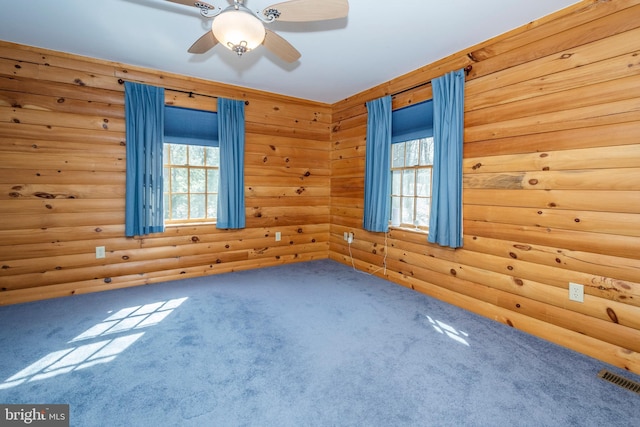 unfurnished room with rustic walls, visible vents, ceiling fan, and carpet flooring