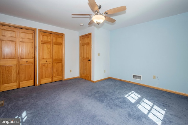 unfurnished bedroom featuring visible vents, baseboards, multiple closets, ceiling fan, and carpet flooring