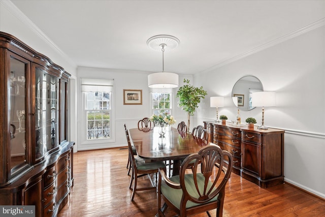 dining space with baseboards, ornamental molding, and wood finished floors