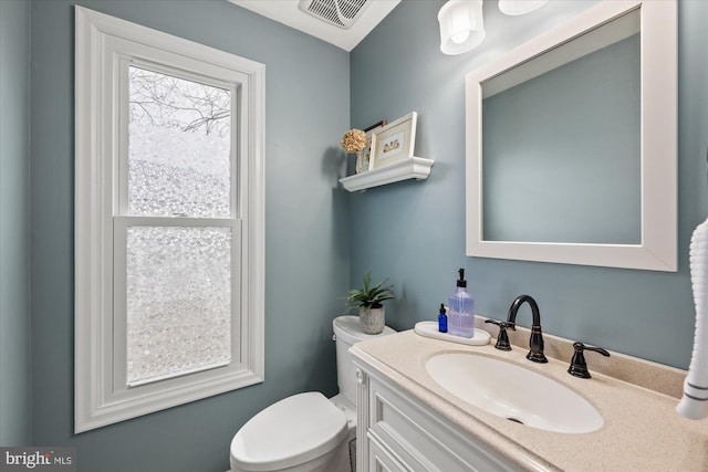 half bathroom featuring toilet, visible vents, and vanity