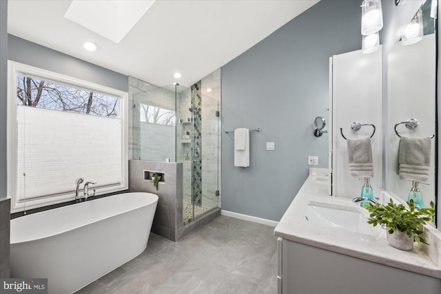 full bath with a freestanding tub, a sink, baseboards, double vanity, and a stall shower