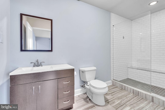 bathroom featuring tiled shower, vanity, and toilet