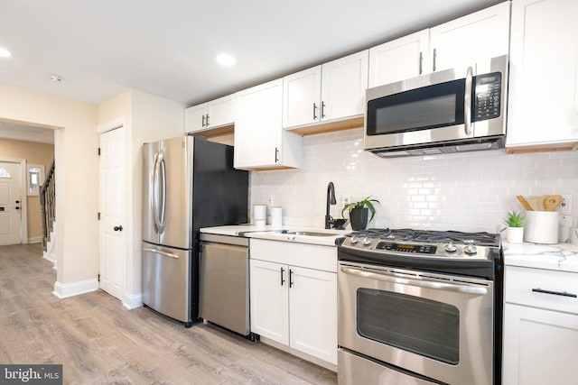 kitchen with light wood-style floors, white cabinetry, appliances with stainless steel finishes, and decorative backsplash