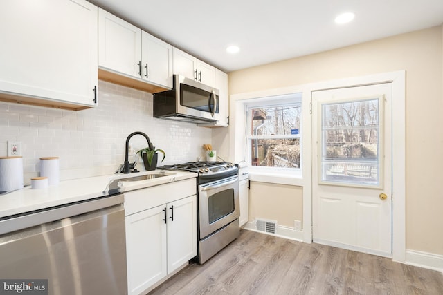 kitchen featuring light countertops, light wood-style flooring, appliances with stainless steel finishes, white cabinetry, and a sink