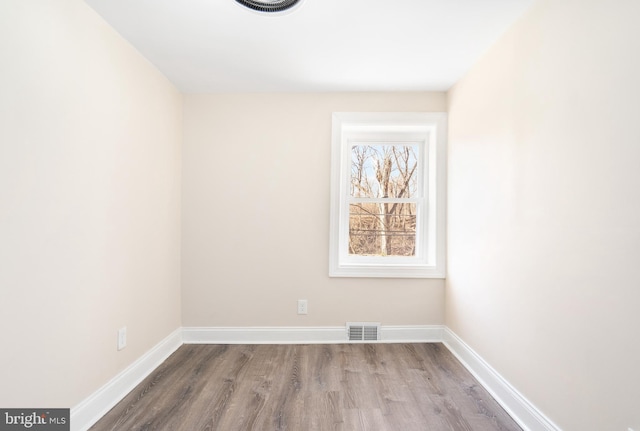 unfurnished room with wood finished floors, visible vents, and baseboards