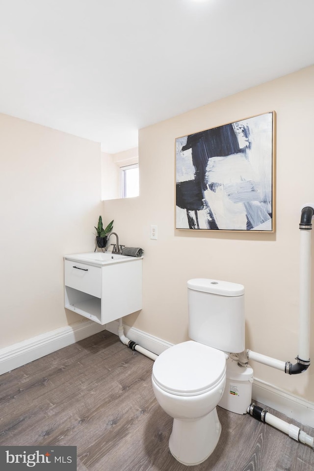 bathroom with baseboards, toilet, and wood finished floors