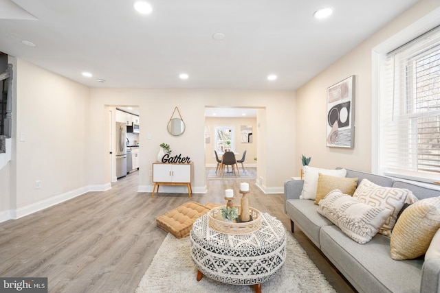 living area featuring recessed lighting, light wood-style flooring, and baseboards