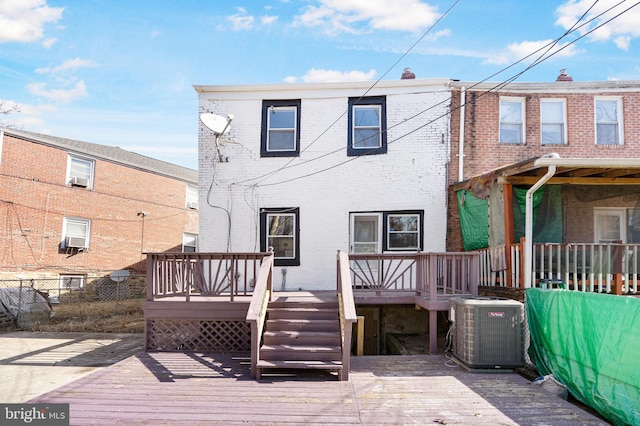 rear view of property with fence, a deck, cooling unit, and brick siding