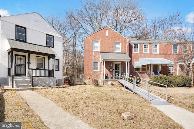 view of front facade with covered porch, brick siding, and a front lawn