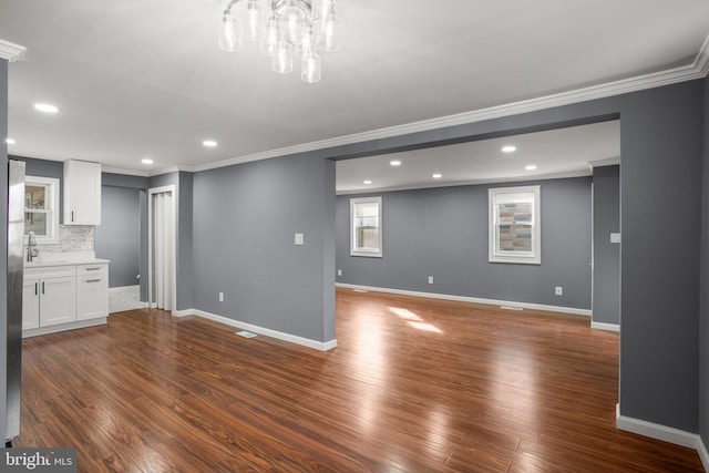 unfurnished living room with ornamental molding, a chandelier, and dark hardwood / wood-style flooring