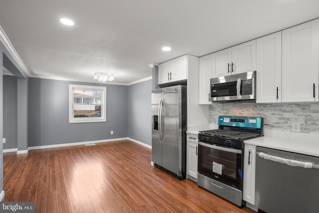 kitchen featuring dark wood-type flooring, white cabinetry, crown molding, stainless steel appliances, and decorative backsplash