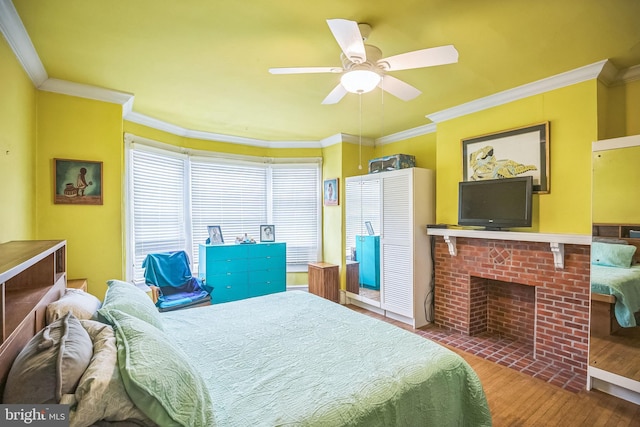 bedroom featuring a brick fireplace, ceiling fan, ornamental molding, and wood finished floors