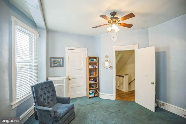 sitting room with a ceiling fan, baseboards, carpet flooring, and an upstairs landing