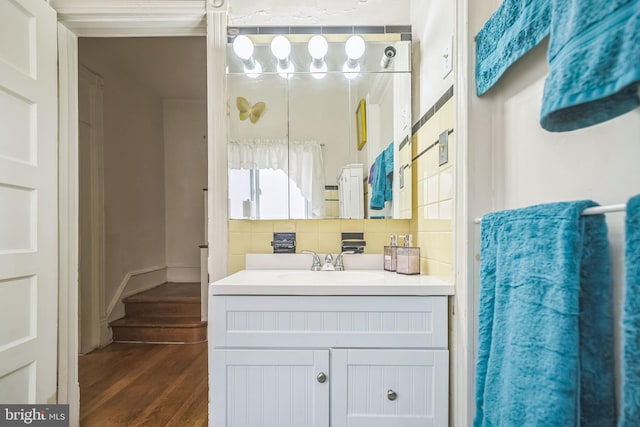 bathroom featuring wood finished floors, backsplash, and vanity