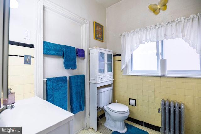 bathroom with toilet, radiator heating unit, tile walls, and tile patterned floors