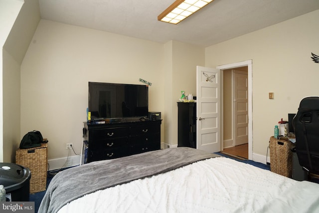 bedroom with lofted ceiling and baseboards