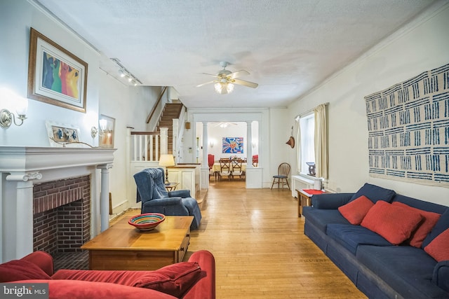 living area with light wood-style flooring, stairs, a textured ceiling, and a ceiling fan