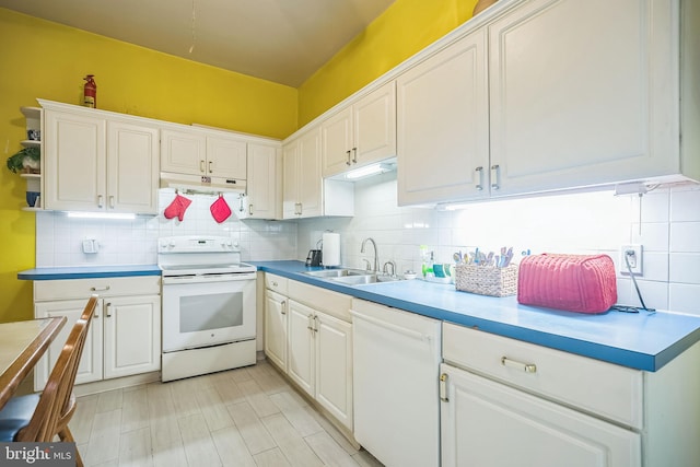 kitchen with white appliances, a sink, and white cabinetry