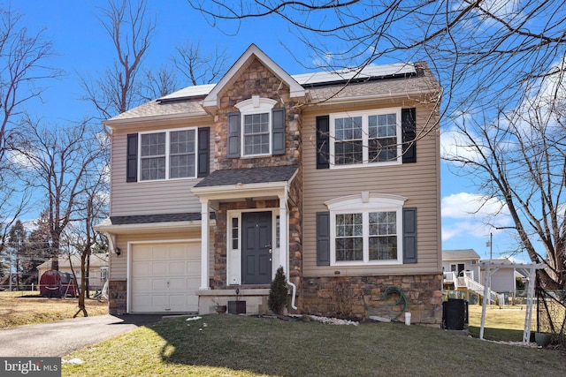 view of front facade with a garage, a front yard, and solar panels