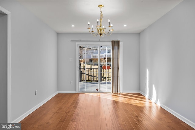 unfurnished dining area with wood-type flooring and a chandelier