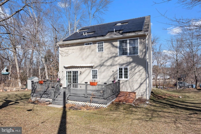 back of house featuring a yard, a deck, and solar panels