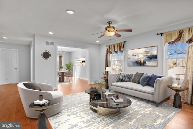 living room featuring ceiling fan with notable chandelier, a wealth of natural light, and light hardwood / wood-style floors