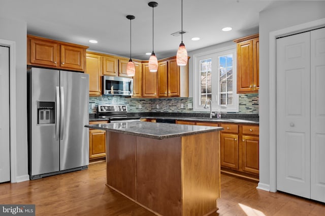 kitchen with tasteful backsplash, light hardwood / wood-style flooring, a kitchen island, pendant lighting, and stainless steel appliances