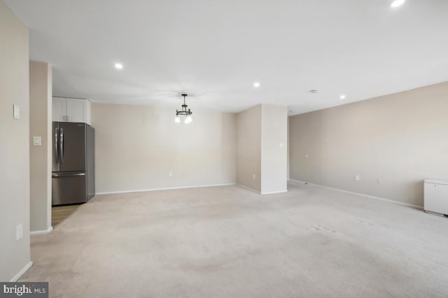 unfurnished living room featuring light carpet and a notable chandelier