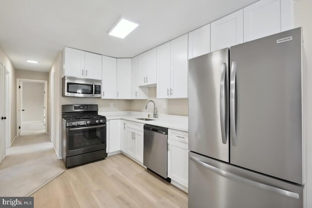 kitchen featuring white cabinetry, appliances with stainless steel finishes, sink, and light hardwood / wood-style flooring