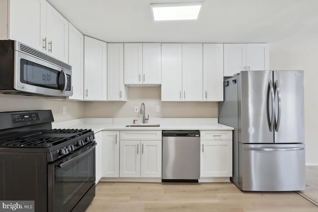 kitchen with sink, light hardwood / wood-style flooring, white cabinets, and appliances with stainless steel finishes