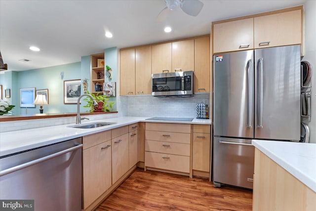 kitchen featuring stainless steel appliances, light countertops, light brown cabinetry, a sink, and wood finished floors