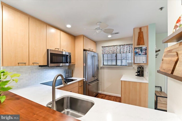 kitchen featuring tasteful backsplash, appliances with stainless steel finishes, light countertops, and a sink