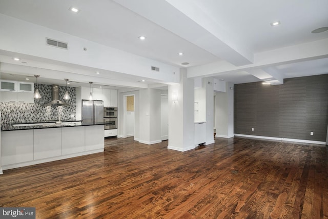 unfurnished living room featuring beamed ceiling and dark hardwood / wood-style flooring