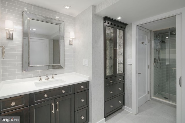 bathroom featuring vanity, a shower with shower door, and decorative backsplash