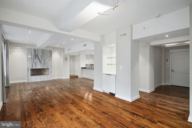 unfurnished living room with dark hardwood / wood-style flooring, beam ceiling, and a high end fireplace